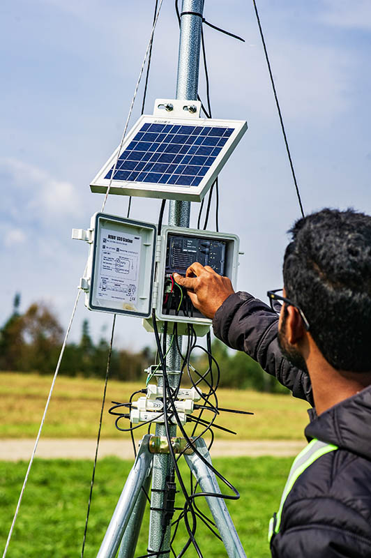 Tharindu Kulasinghe (PhD candidate) inspects weather station at the forage field in Cormack